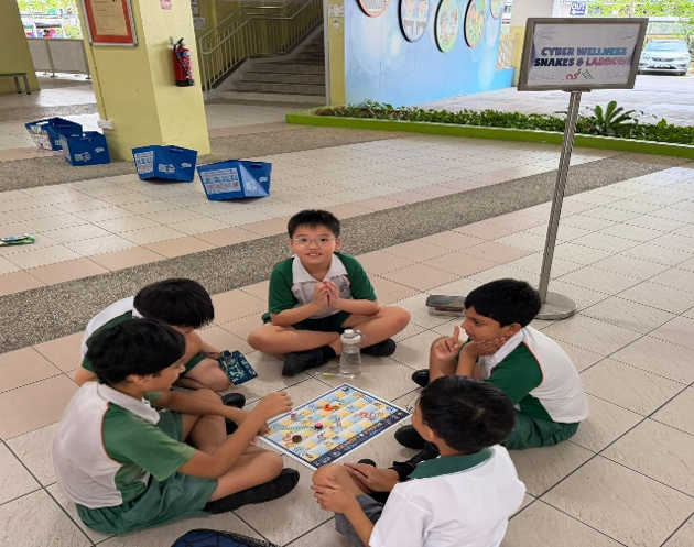 Students playing a cyber wellness board game during a school activity.