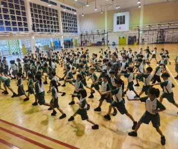 Students participating in a group exercise session in the school hall.