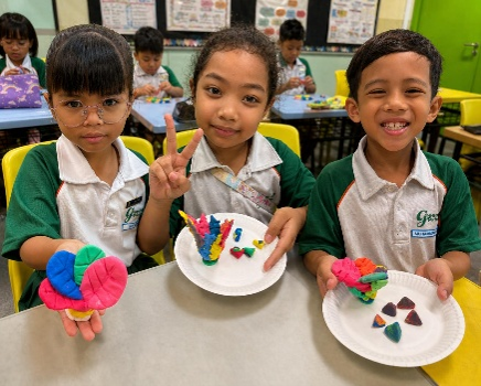 Students proudly displaying colourful handmade crafts in the classroom.
